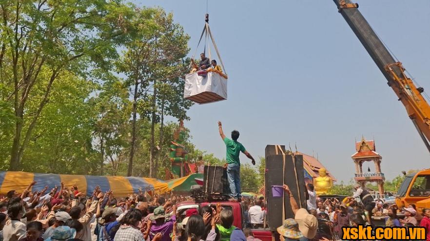 Hai ca sĩ Thái Lan đứng trên cần cẩu rải tiền trúng số cho người dân